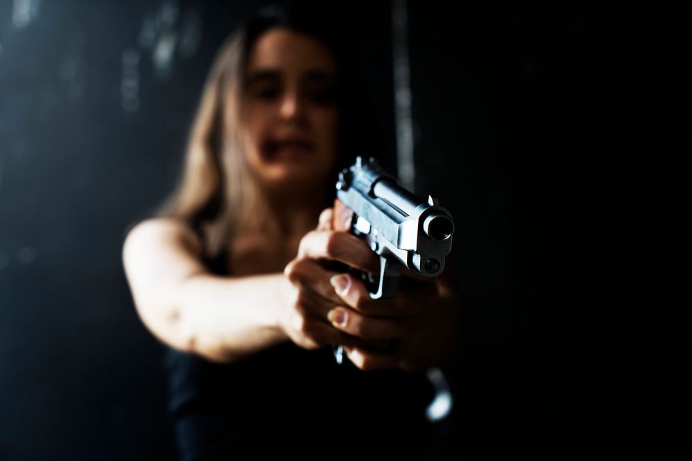 Bruised woman pointing a gun