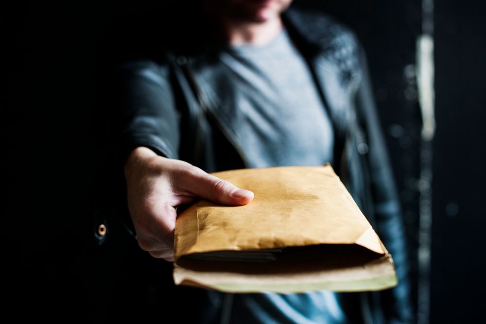 Handing a thick brown envelope