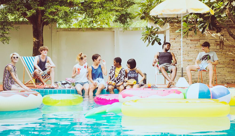 Group of diverse friends enjoying the pool with inflatable tubes