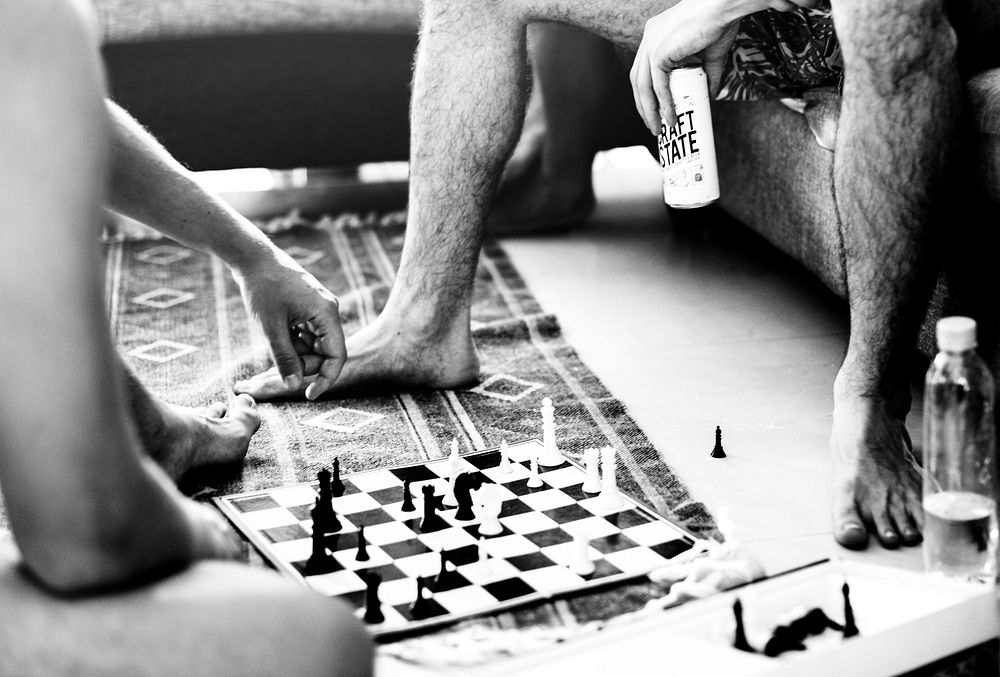 Closeup of man sitting on the floor playing chess with friends