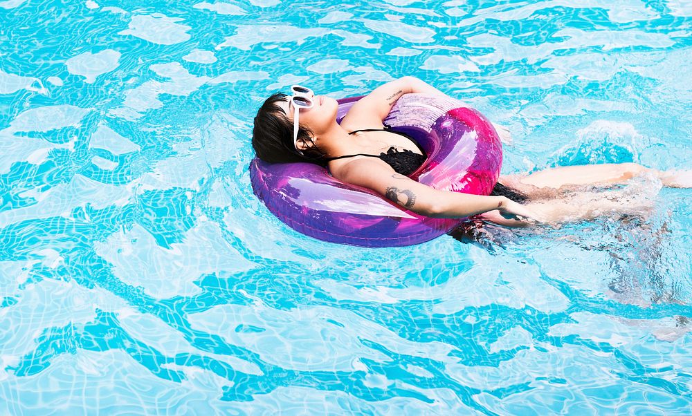 Asian woman floating in the swimming pool with inflatable tube