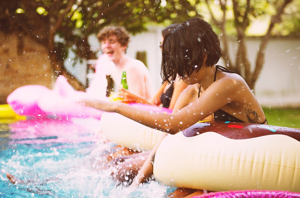 Group of diverse friends enjoying the pool with inflatable tubes