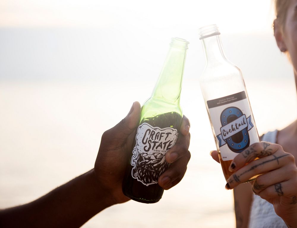 Clsoeup of caucasian woman clinking beer bottle with black man at the beach