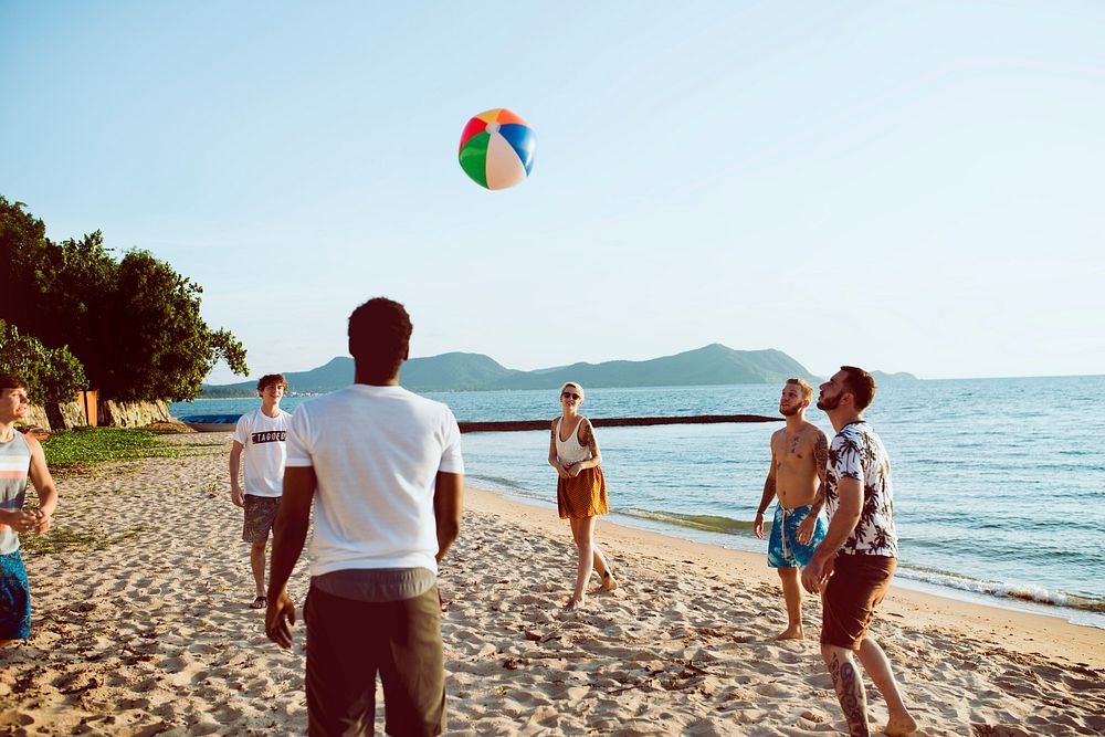 Group of diverse friends playing beach ball together