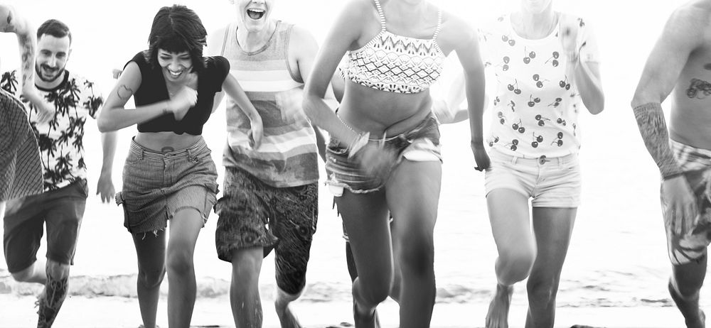 Group of diverse friends running at the beach together