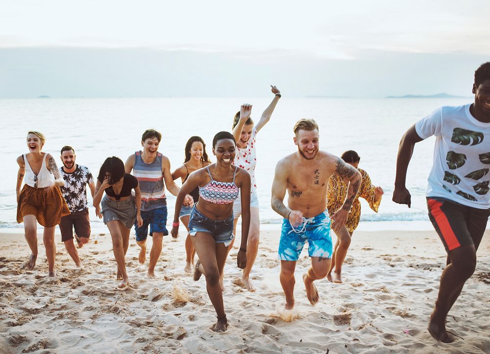 Group of diverse friends running at the beach together