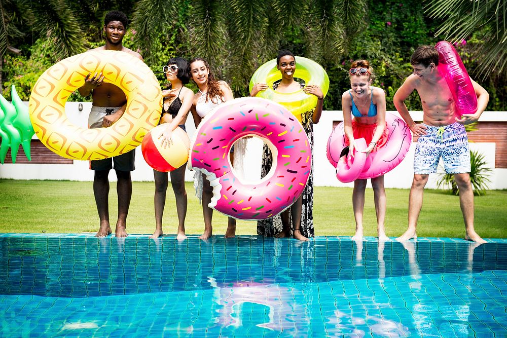 Group of diverse friends holding inflatable tubes by the pool