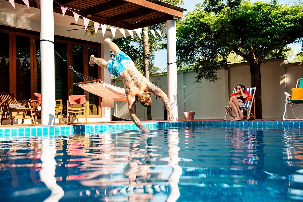 Tattooed man jumping to the pool