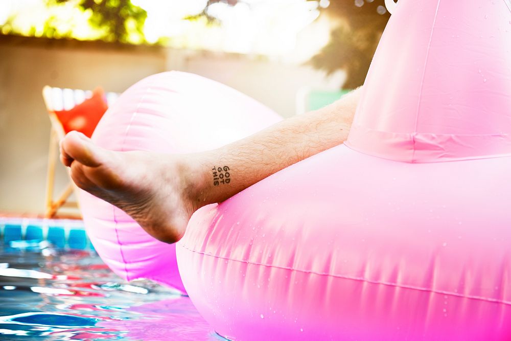 Closeup of tattooed leg on inflatable tube in swimming pool