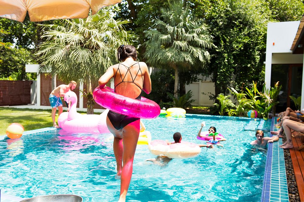 Asian woman jumping to the pool with inflatable tube