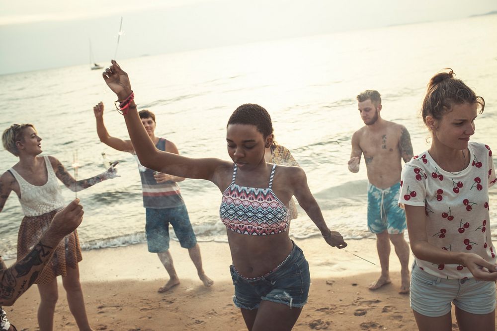 Group of diverse friends enjoying sparklers at the beach together
