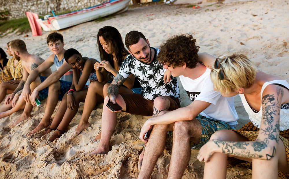 Group of diverse friends sitting at the beach together
