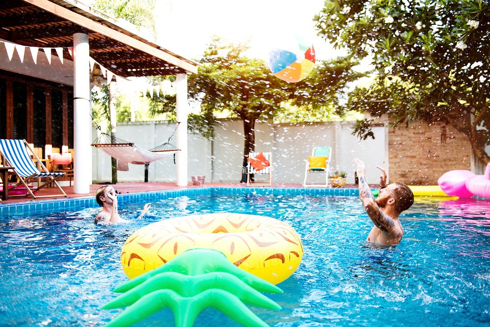 Diverse men playing beach inflatable ball in swimming pool enjoying summer time
