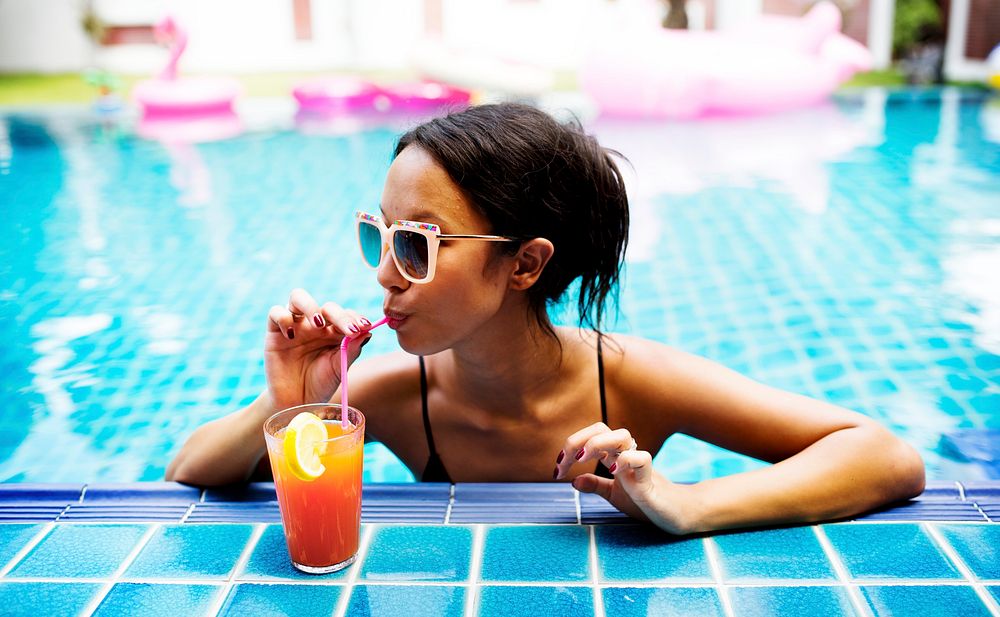 Asian woman drinking juice by the poolside