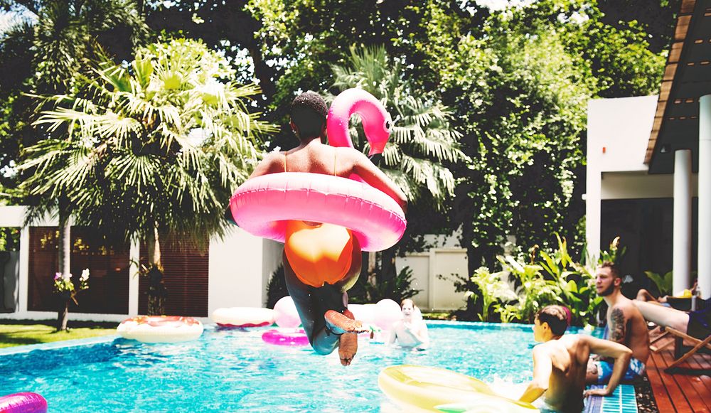 An African woman jumping into the pool with inflatable floats