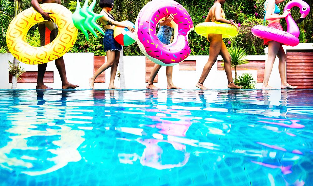 A diverse group of friends enjoying summer time by the pool with inflatable floats
