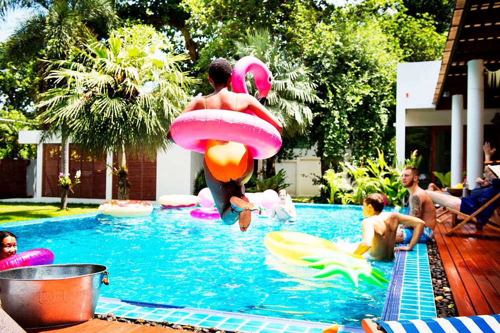 An African woman jumping into the pool with inflatable floats
