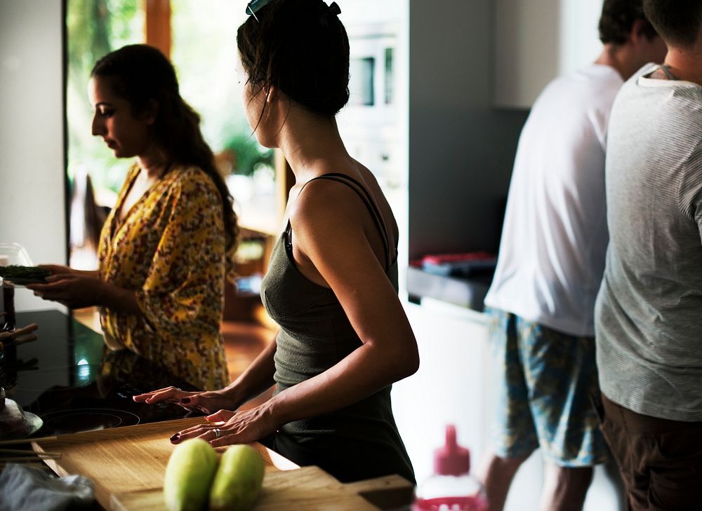 A diverse group of friends preparing food in the kitchen together