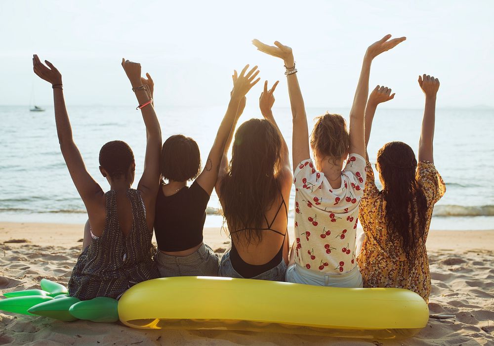 Group of diverse women sitting at the beach together