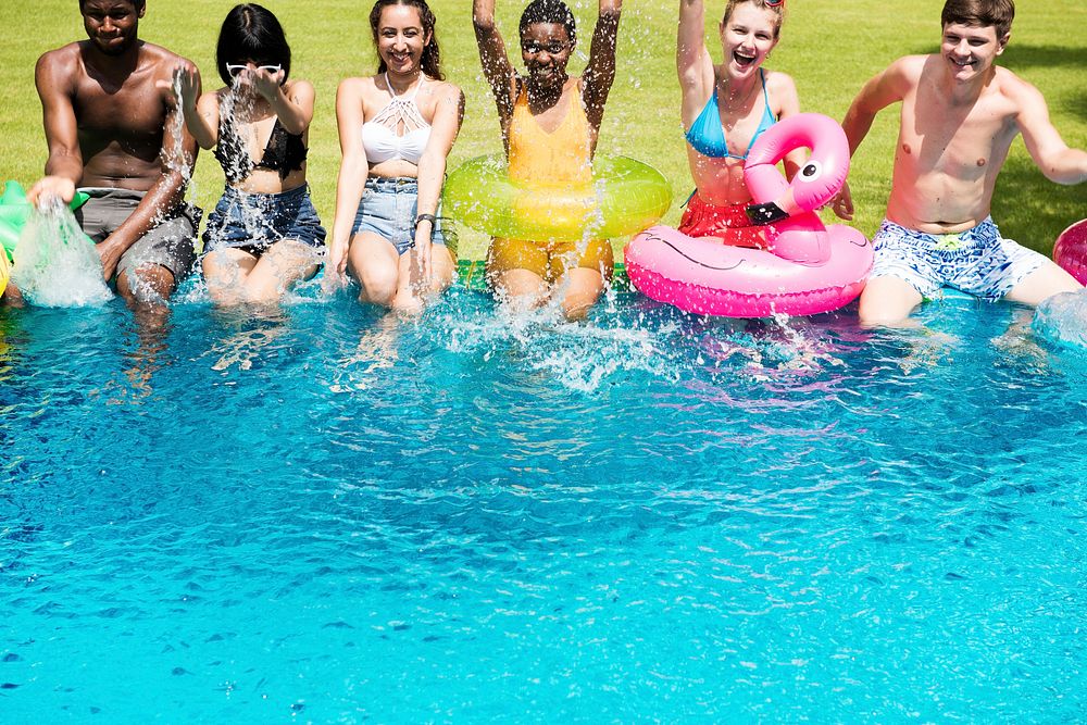 Group of diverse friends splashing water at the swimming pool