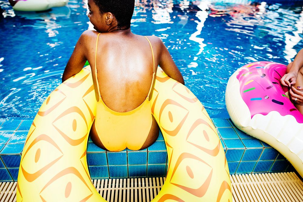 Closeup of african descent woman sitting by the pool with inflatable tubes