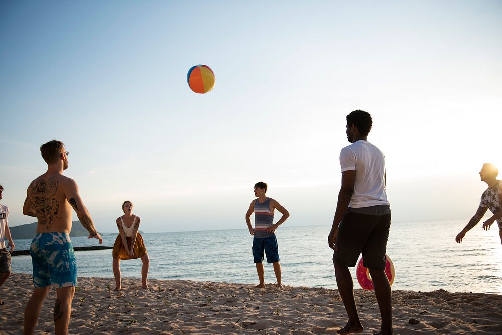 Group of diverse friends playing beach ball together