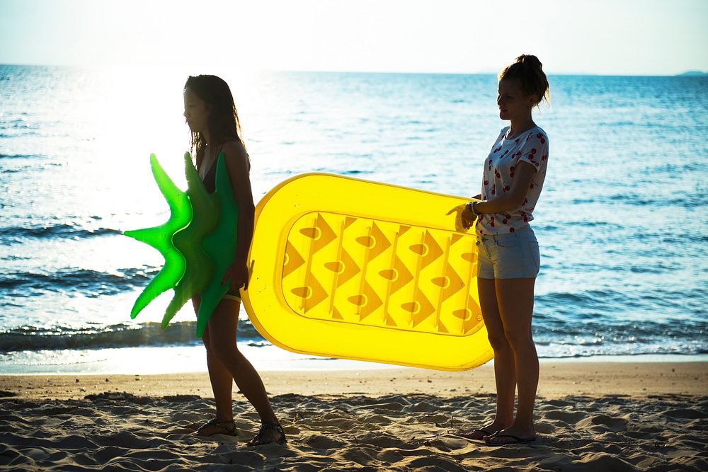Diverse women with pineapple inflatable at the beach