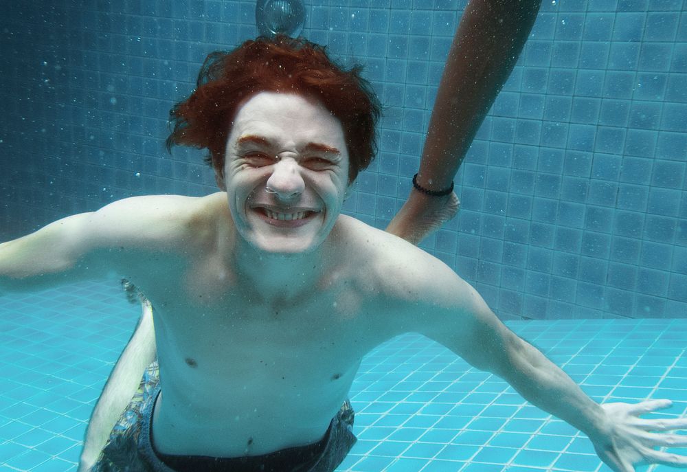 Caucasian man smiling underwater in swimming pool