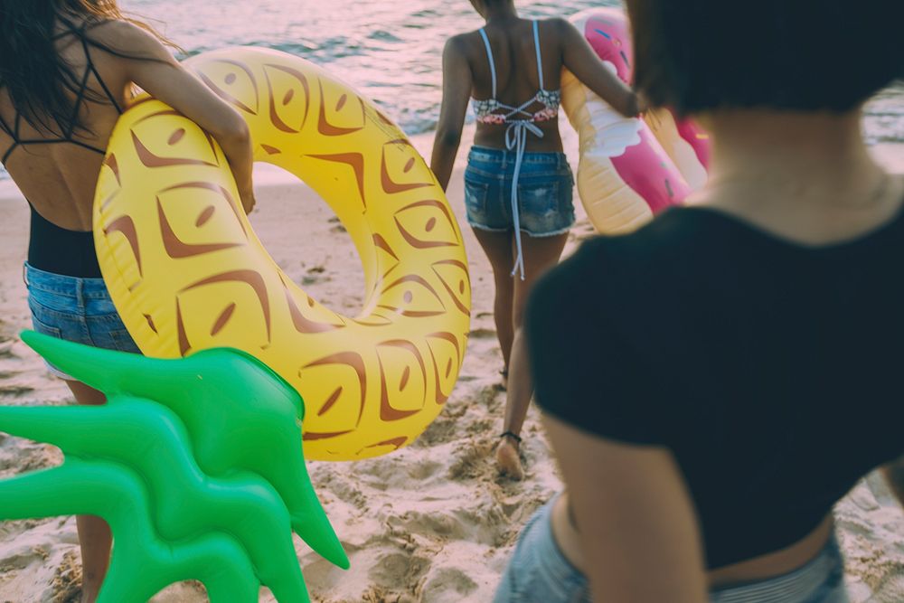 Group of diverse women walking at the beach with inflatable tubes