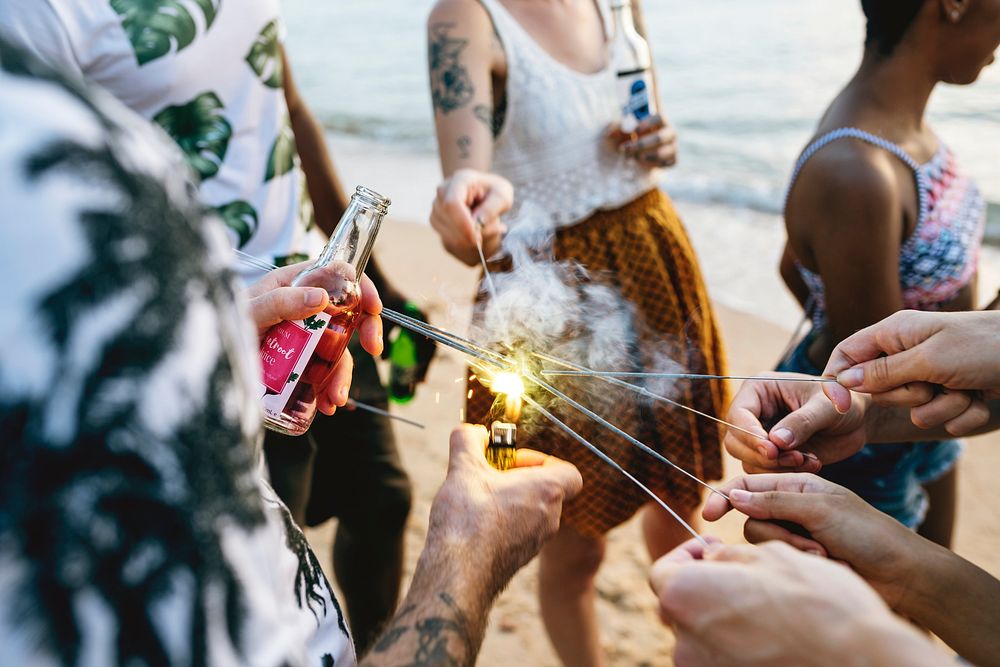 A diverse group of friends enjoying sparklers at the beach together