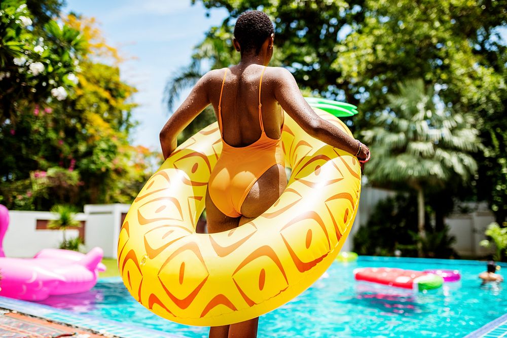 An African woman standing by the pool with an inflatable float and enjoying the summer time