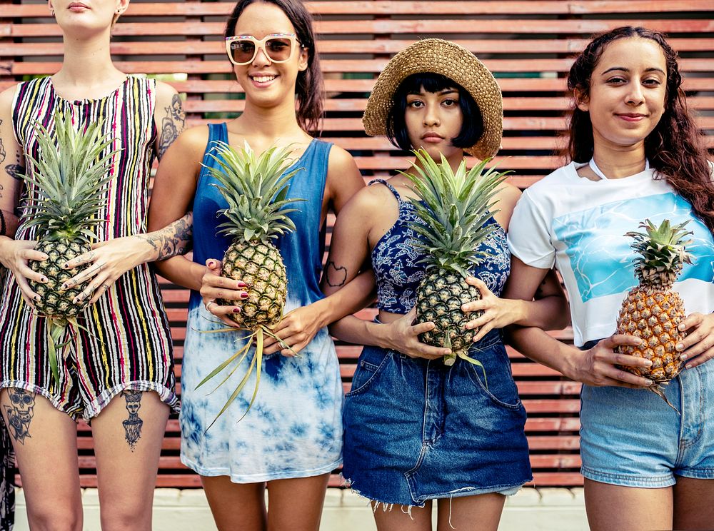 Group of diverse women standing holding pineapple together