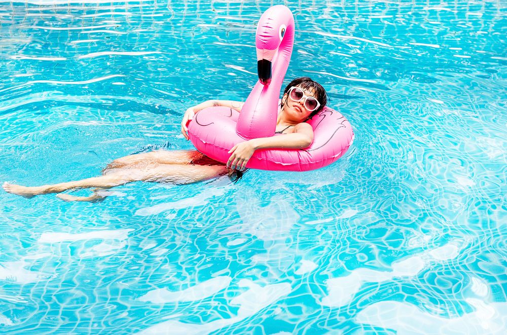 An Asian woman floating in the pool with inflatable floats