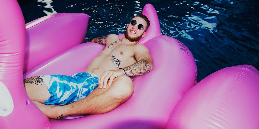 Caucasian tattooed man floating in the swimming pool by inflatable