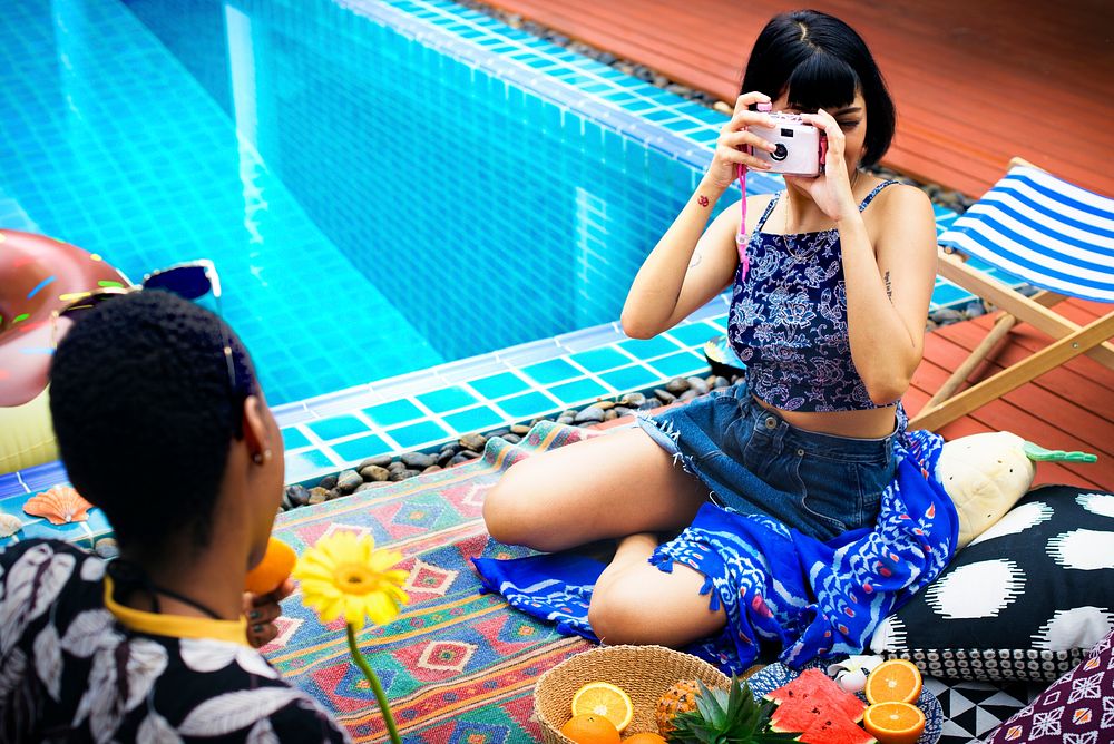 Girl using camera taking a photo by a swimming pool