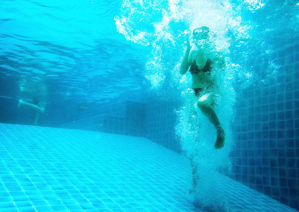 Woman jumping in to a swimming pool