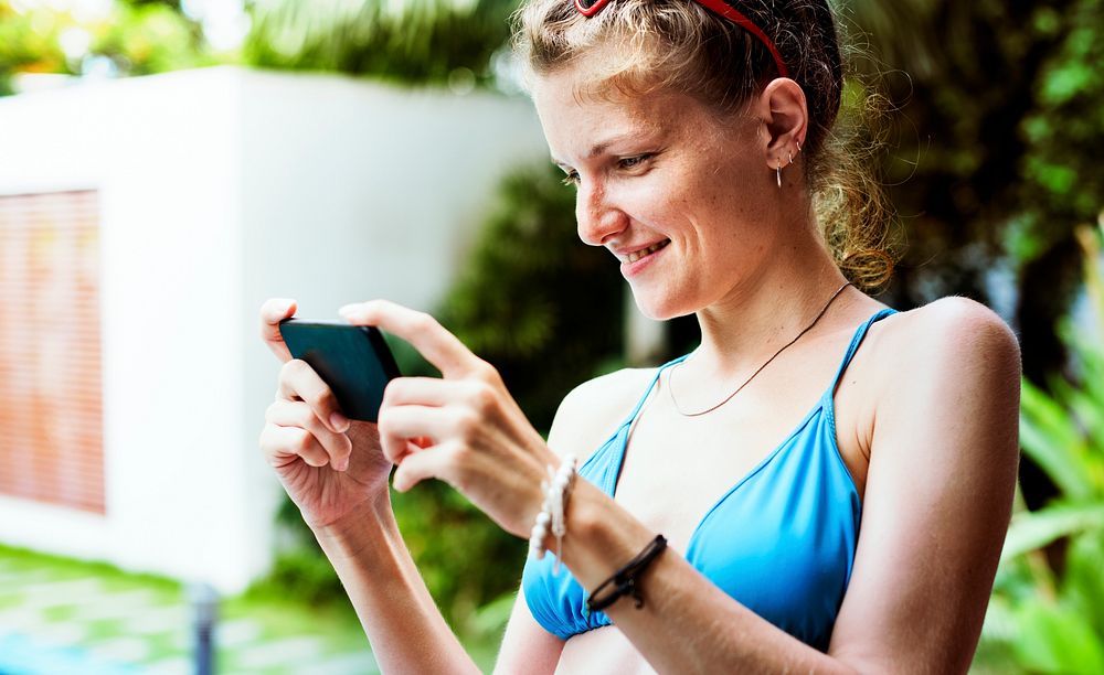 Caucasian woman in swimwear holding smart-phone