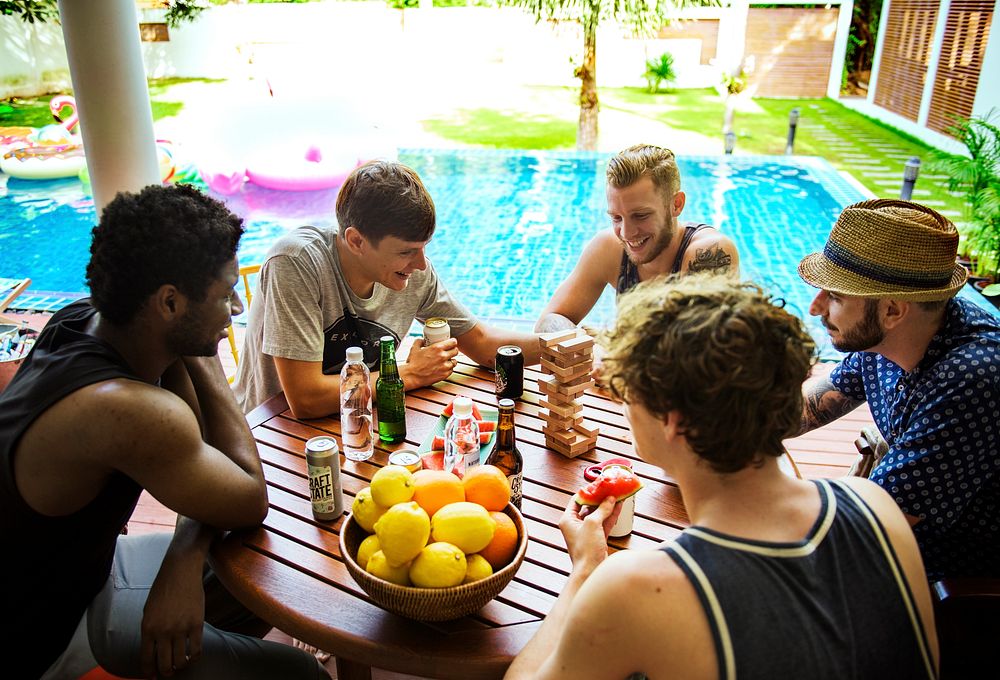 Group of guys friends playing stack game together on the poolside