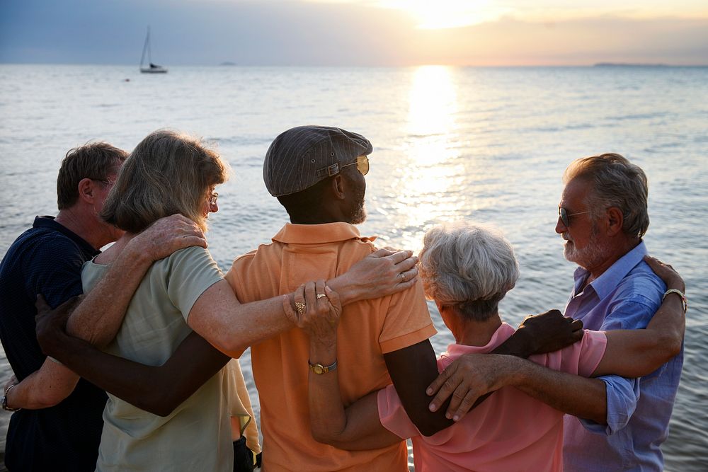 Rear view of diverse senior adult standing together at the beach