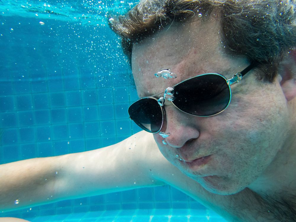 Man with sunglasses diving in a pool