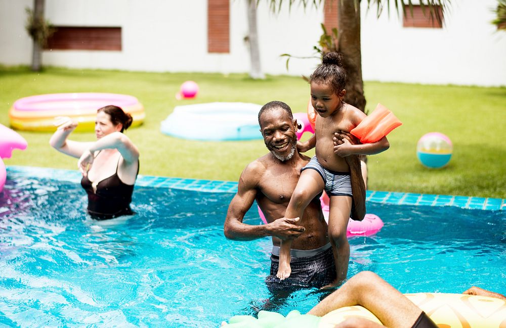 African descent parent embracing their child in a pool