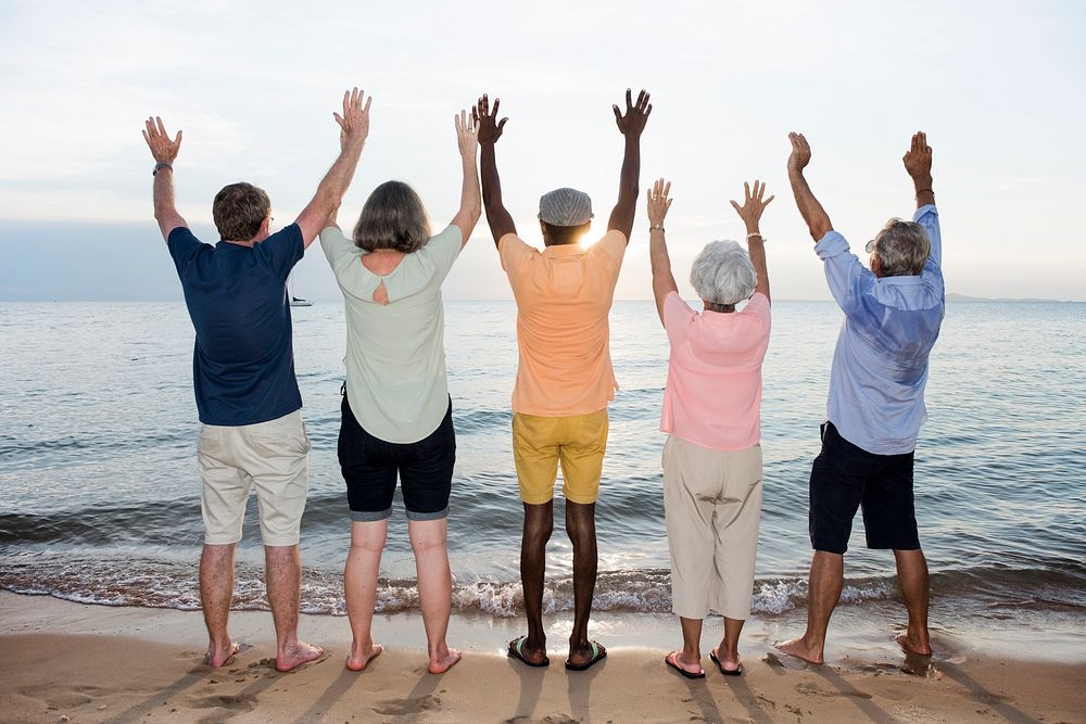 Group of senior friends arm raised on the beach