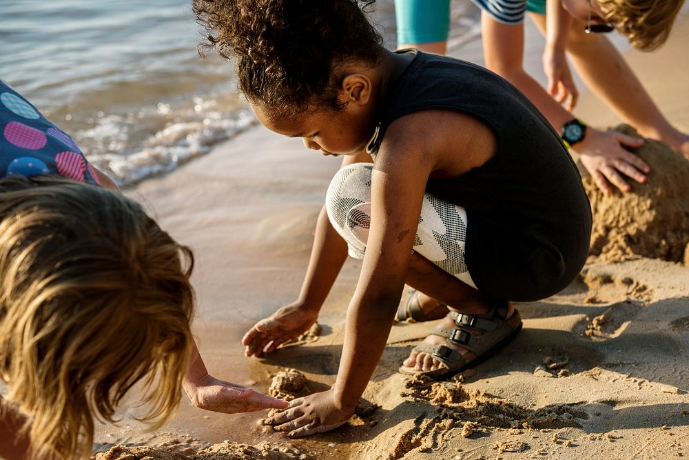 Closeup of diverse kids playing with the sand together at the beach