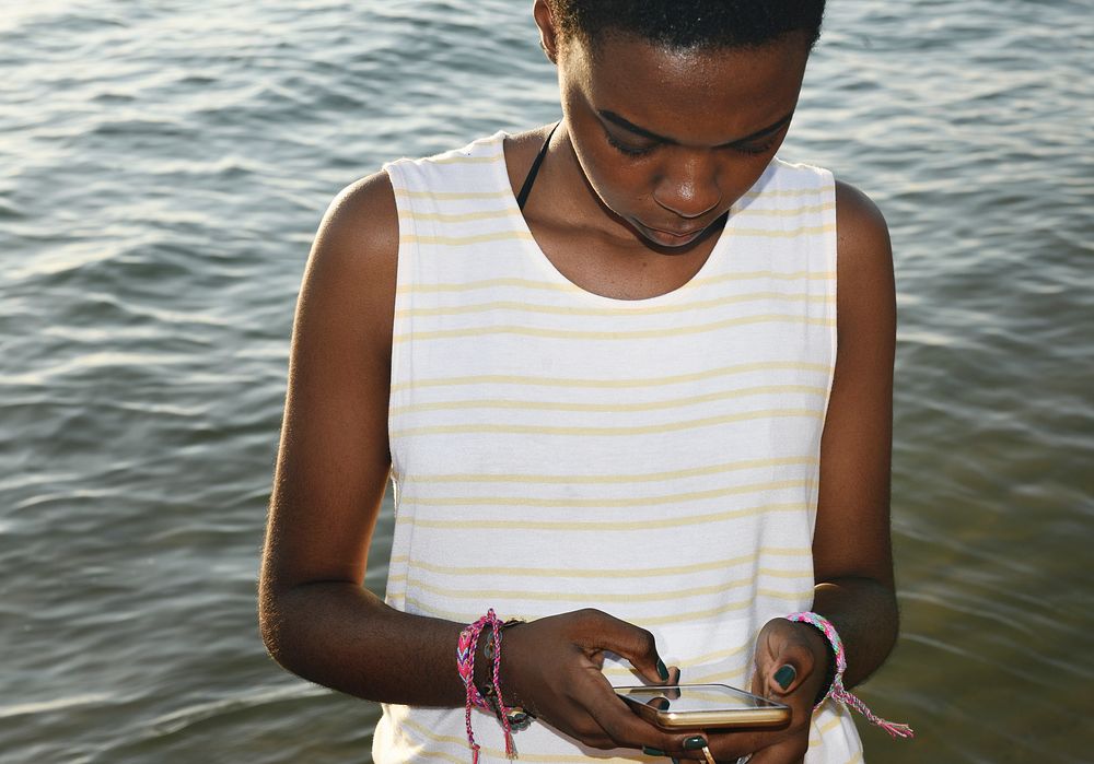 African descent woman using mobile phone by the sea