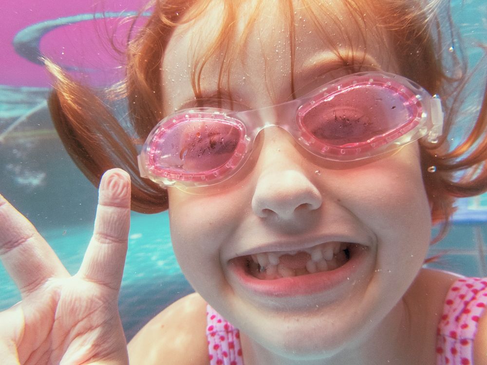 Girl with goggles smiling to camera in the pool
