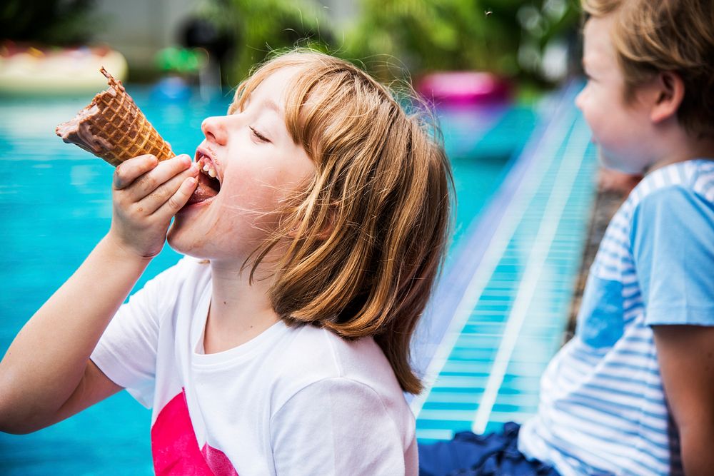 Closeup of caucasian girl eating ice cream by the pool