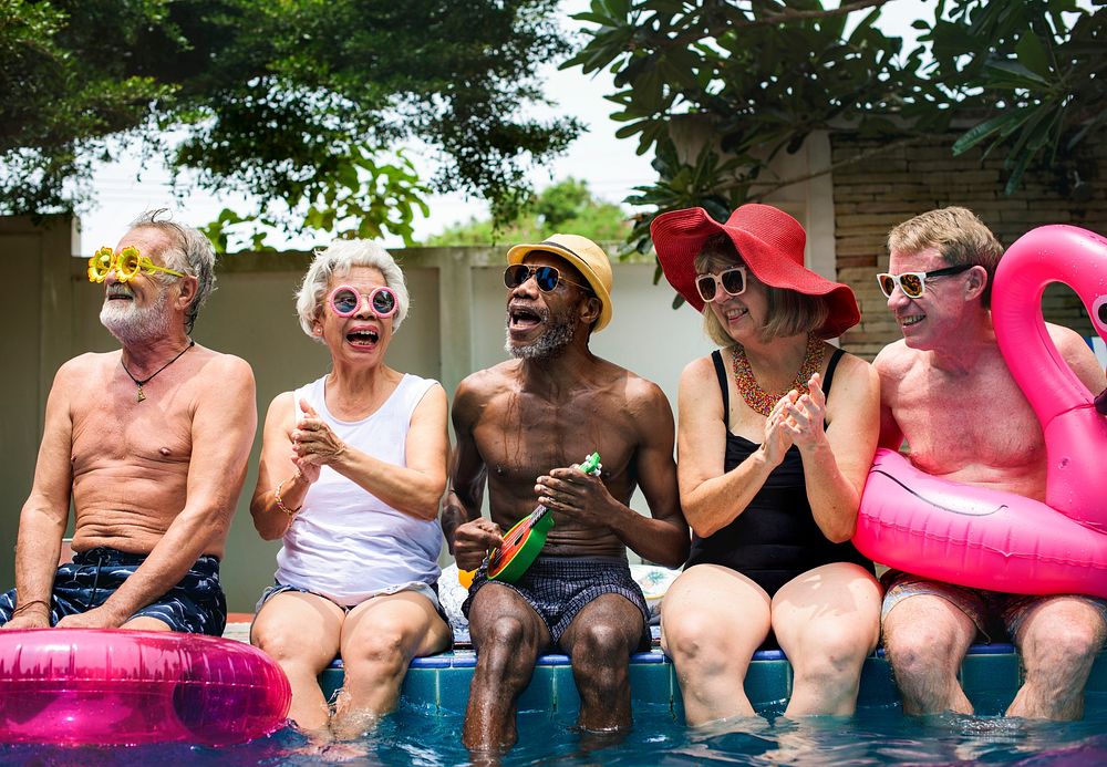 Group of diverse senior adults sitting by the pool enjoying summer together