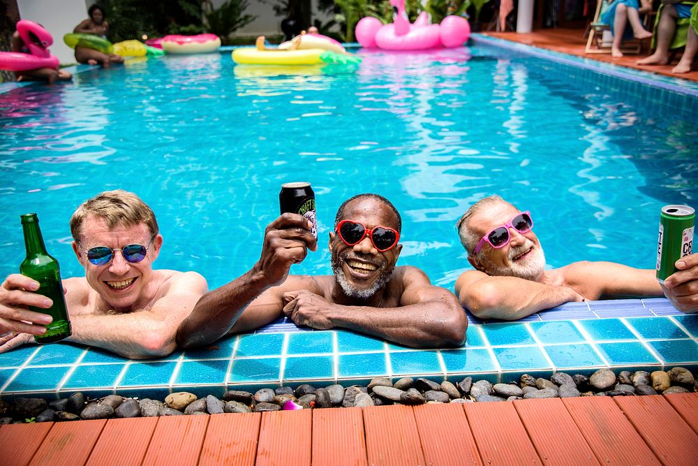 Cheerful diverse senior men drinking beer by the pool