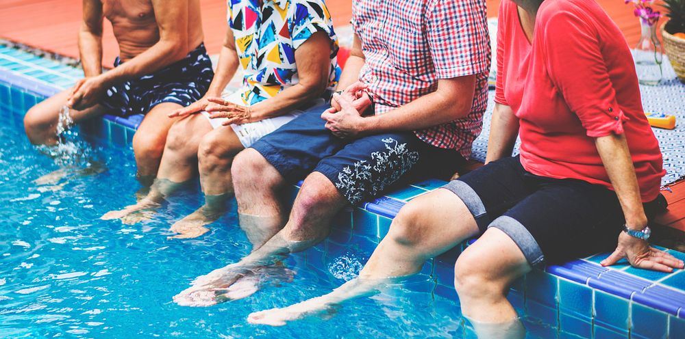 Group of diverse senior friends splashing water at the swimming pool