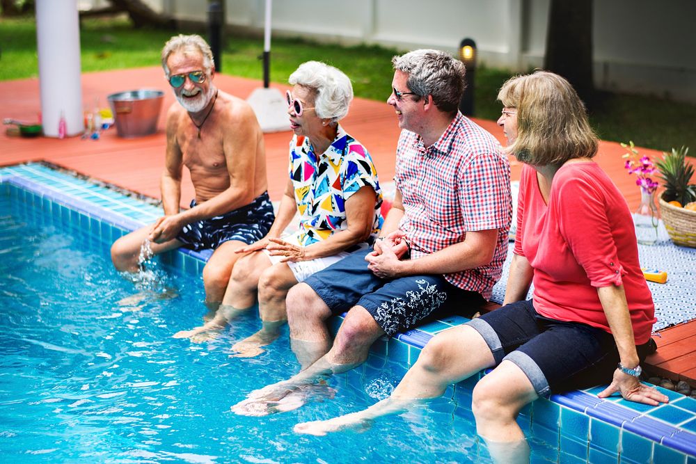 Group of diverse senior friends splashing water at the swimming pool